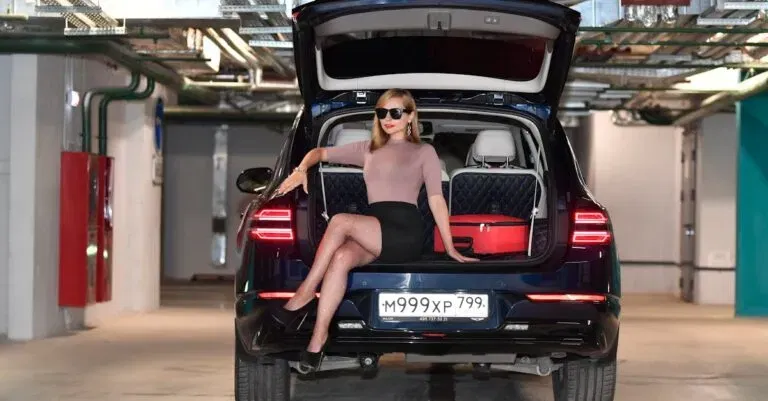 Elegant Woman Posing In A Parking Garage With A Car And Luggage.