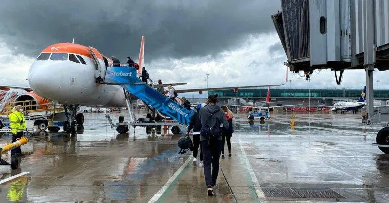 Passengers Boarding An Aircraft At Edinburgh Airport On A Rainy Day, Highlighting Travel Dynamics.