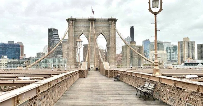 Iconic Brooklyn Bridge View With Manhattan Skyline In The Background, Featuring Classic Architecture.