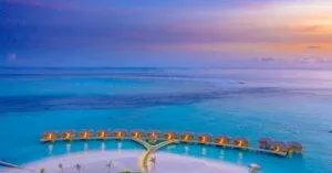 A Breathtaking Aerial Shot Of Overwater Bungalows In The Maldives During Sunset.