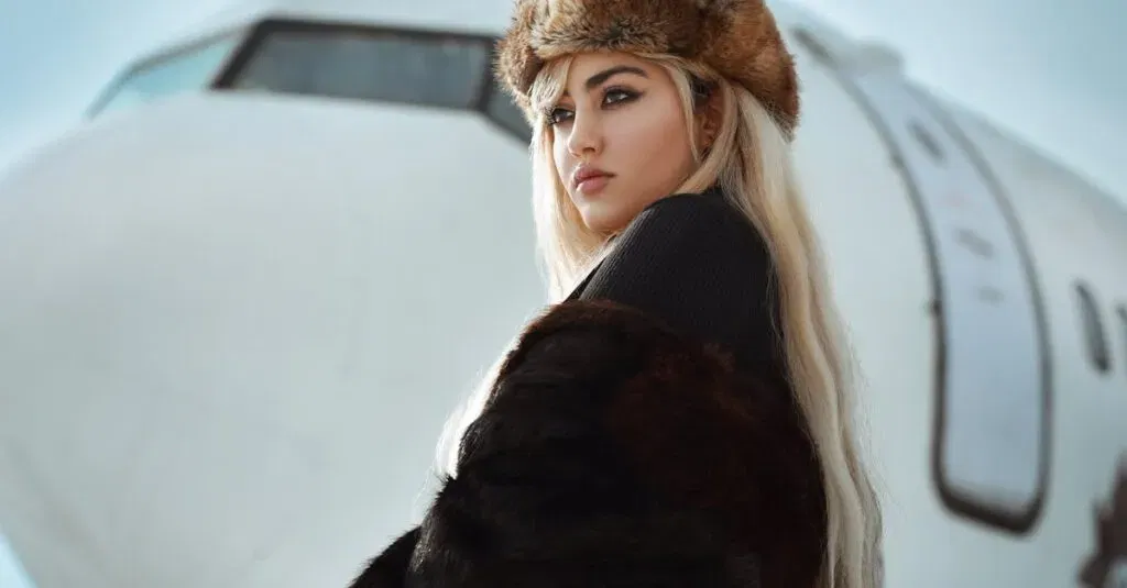 Stylish Woman In Fur And Hat Posing Near Aircraft In Winter Setting.