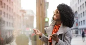 Happy woman with curly hair shopping in the city, reflecting joy and a trendy lifestyle.