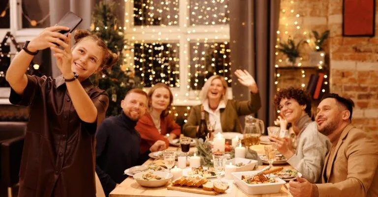 A Joyful Family Capturing A Selfie During A Festive Christmas Dinner Indoors.