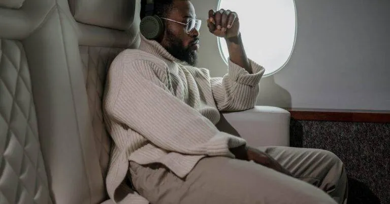 A Man Relaxing With Headphones While Traveling On A Plane, Enjoying Leisure In Comfort.