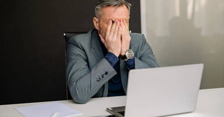 Businessman In Gray Suit Showing Frustration While Working In Office.