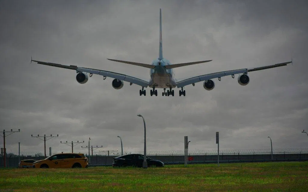 A Passenger Airplane Lands At New York Airport With Cloudy Skies, Showcasing Aviation And Urban Transport.