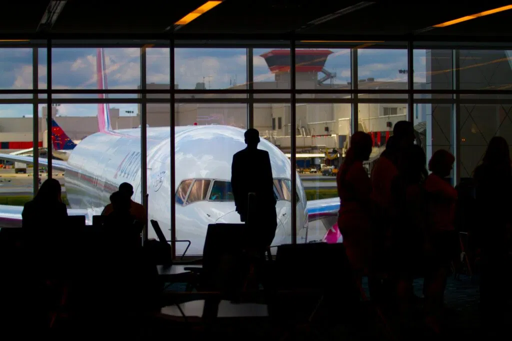 Airporter Nyc In 2026: What Really Happened To The Old Shuttle And Why You Might Want Something Better 2 March 25, 2026 Silhouettes Of Travelers Waiting At An Airport Terminal With An Airplane Visible Through The Window.