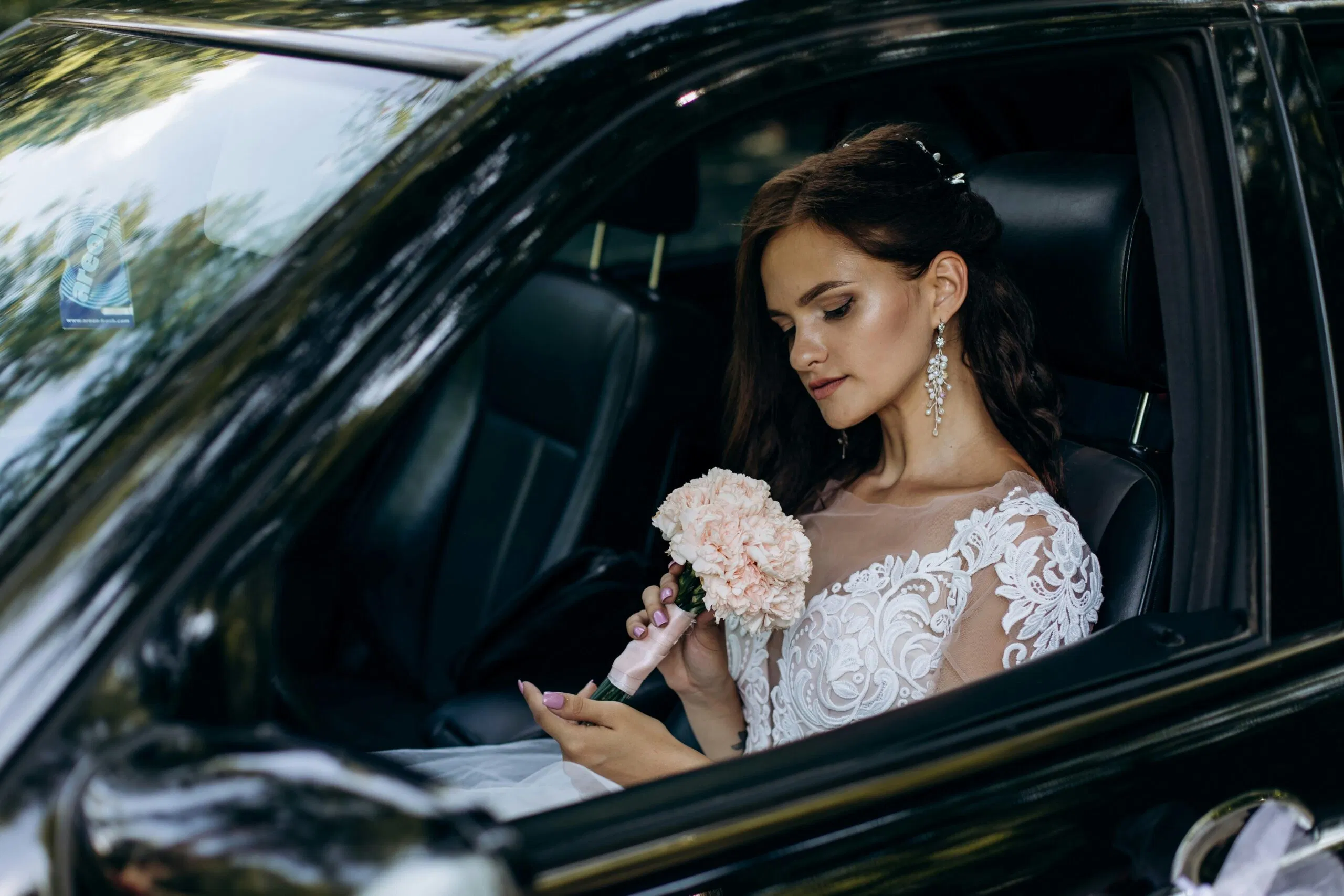 A Bride Wearing A Lace Wedding Dress Holds A Bouquet Sitting In A Car, Ready For Her Wedding Celebration.