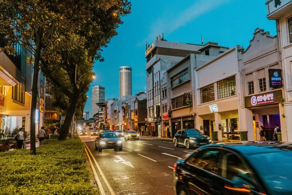 Eco friendly flat rate taxi to JFK — electric and hybrid options for families 2026 Vibrant urban scene showing busy street, historic architecture, and city life at dusk.