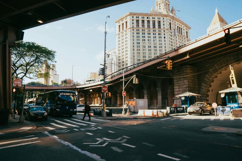 JetBlack Sprinter van corporate group transfer at JFK airport Bustling city street underpass in New York City with vehicles and pedestrians during the day.
