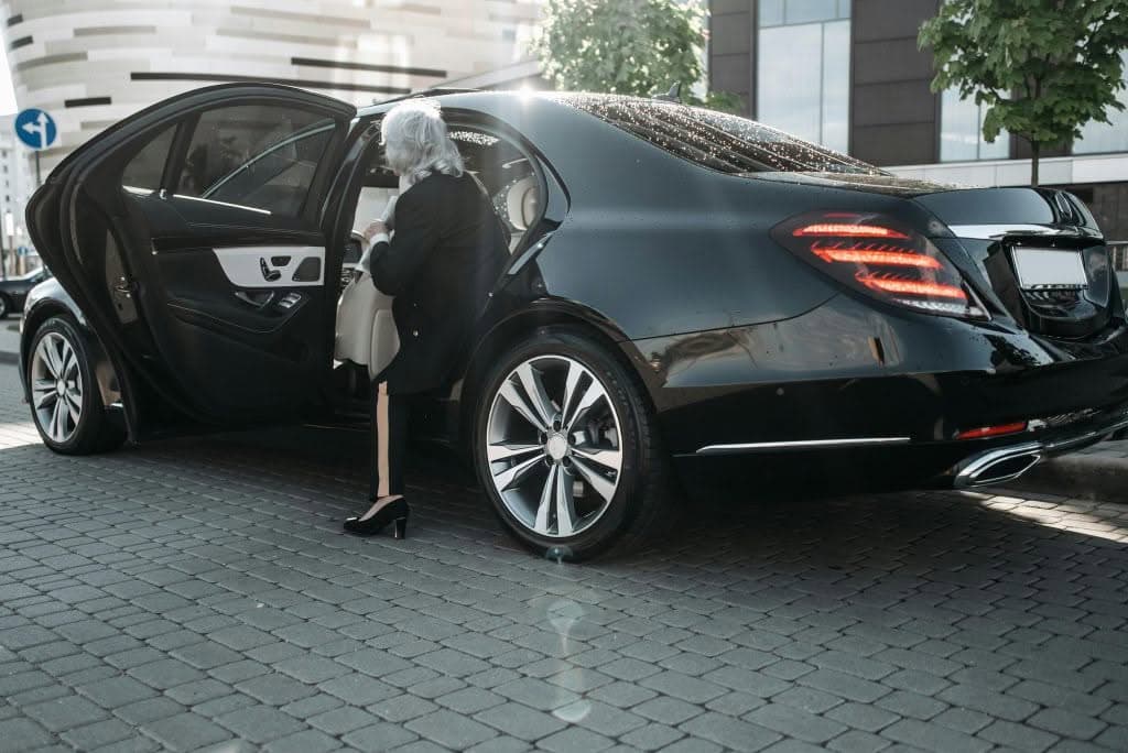 Pexels-Photo-8425413-8425413-1 Senior Businesswoman Stepping Out Of A Sleek Black Luxury Vehicle In A Cityscape.